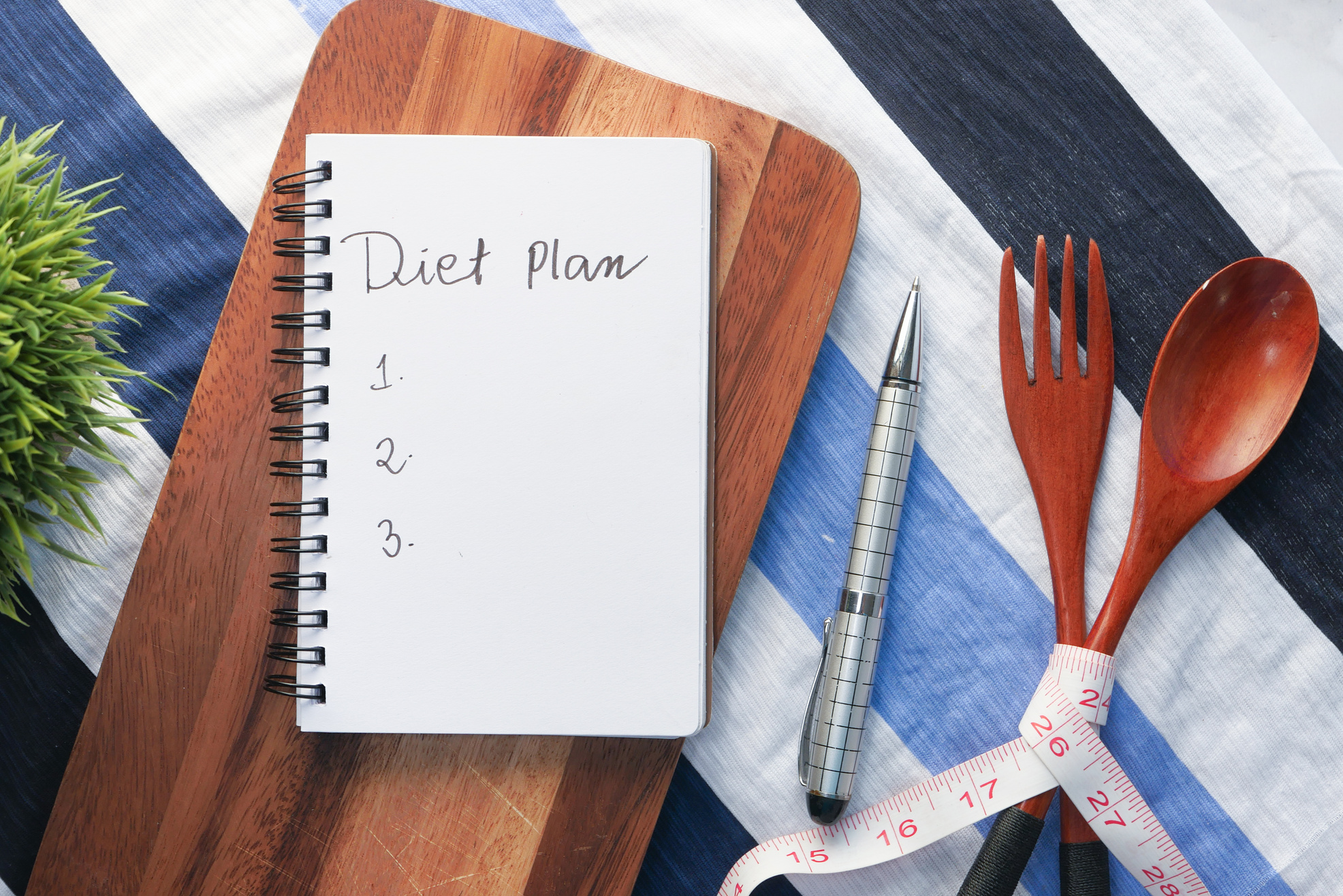 Diet Plan on Chopping Board with Wooden Fork and Spoon on White Table.